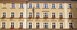Facade of a yellow townhouse with flower boxes on the windows