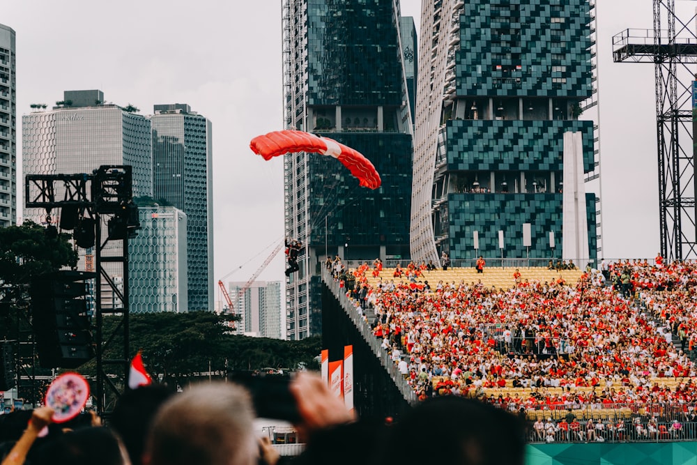 a crowd of people watching a red kite fly in the air