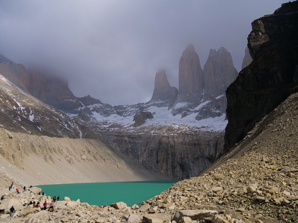 a group of people standing on top of a mountain next to a lake