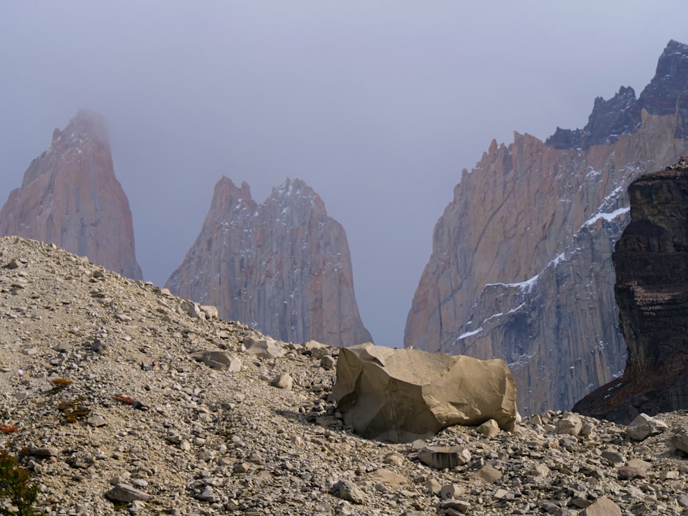 a mountain range with a rock formation in the foreground