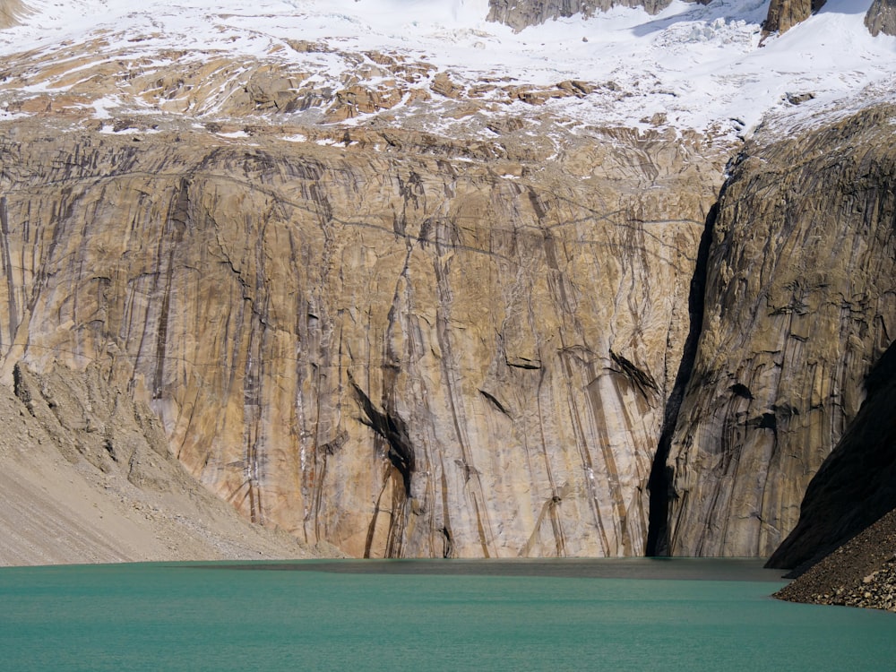 a mountain side with a body of water in front of it