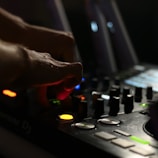 Close-up of Filthyrich’s hands on a MIDI controller surrounded by glowing equipment.