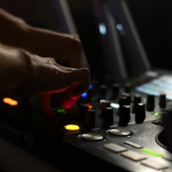 Close-up of DJ hands on mixer with purple neon glow and grunge textures.