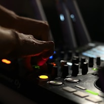 Close-up of DJ hands adjusting sound mixer controls during a private party.