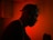 A silhouette of a person wearing headphones against a vibrant red background. The ambient lighting creates a dramatic and focused atmosphere, with the person seemingly engaged in music or audio-related activity.