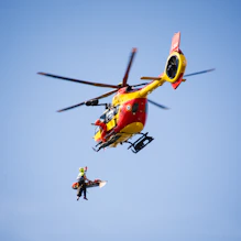a red and yellow helicopter flying through a blue sky