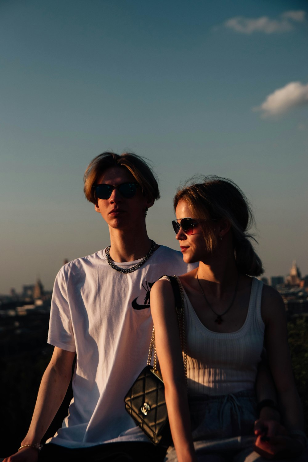 a man and a woman sitting on top of a hill