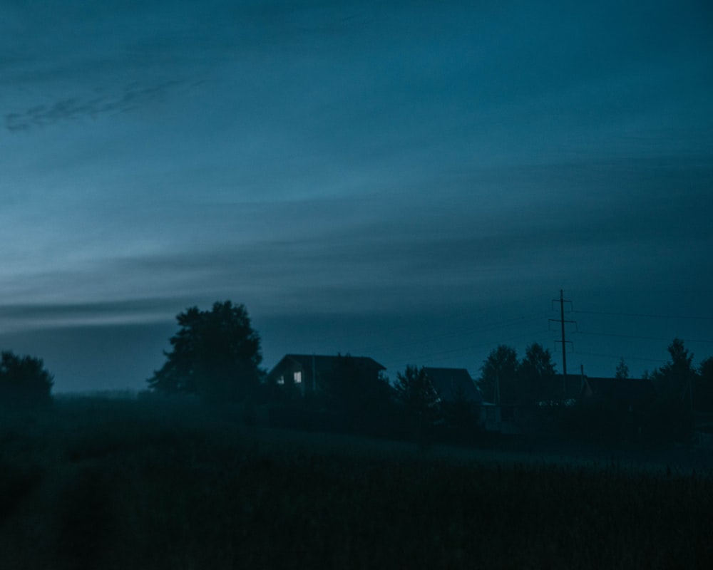a house in a field at night with the moon in the sky