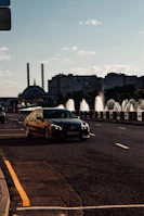 Dynamic cityscape at dusk with a high-end car driving along a wet urban road.