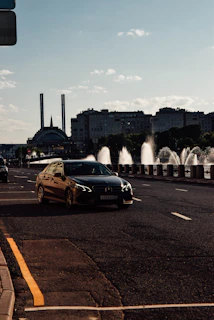 Dynamic cityscape at dusk with a high-end car driving along a wet urban road.