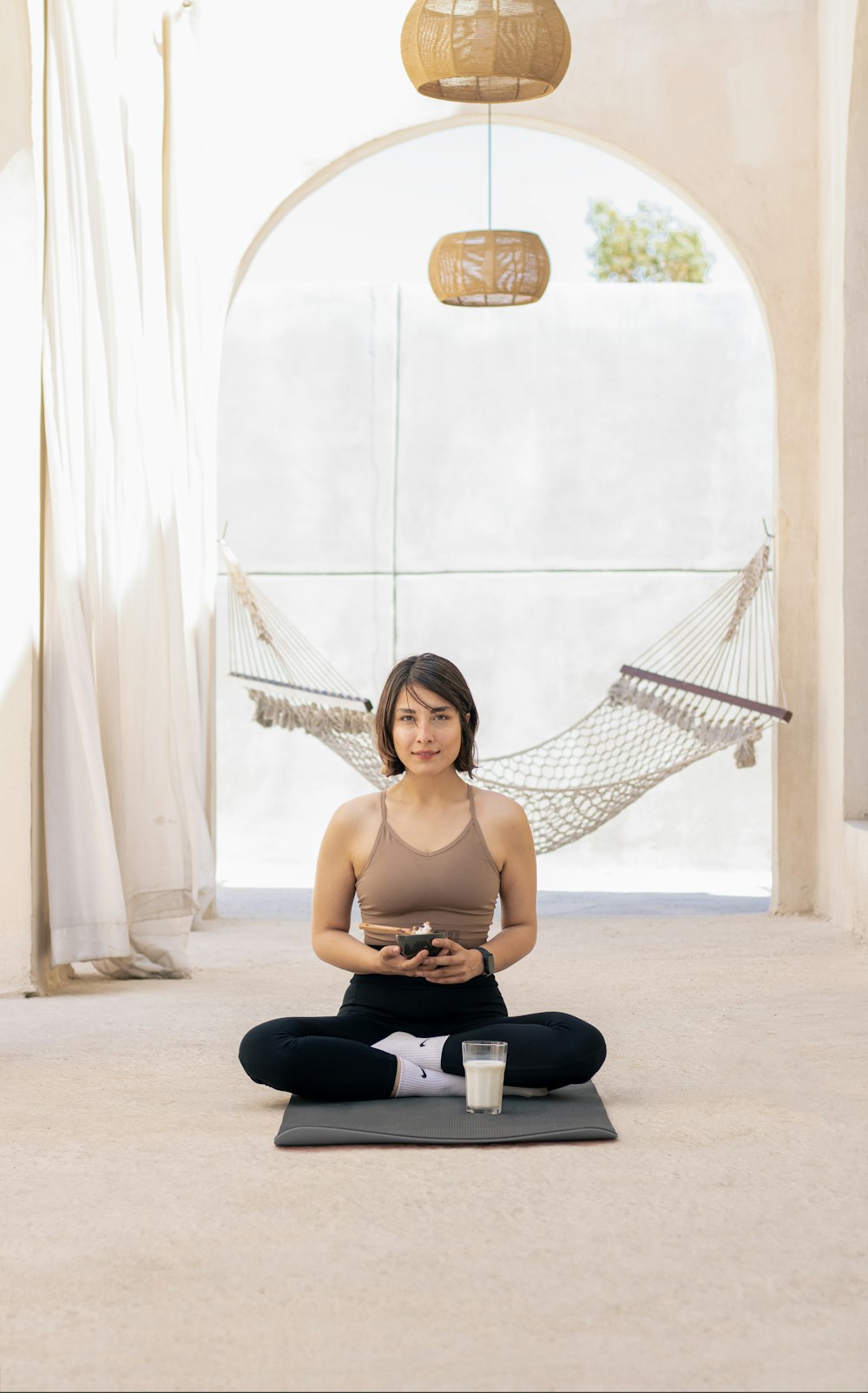a woman sitting on a yoga mat in a hammock