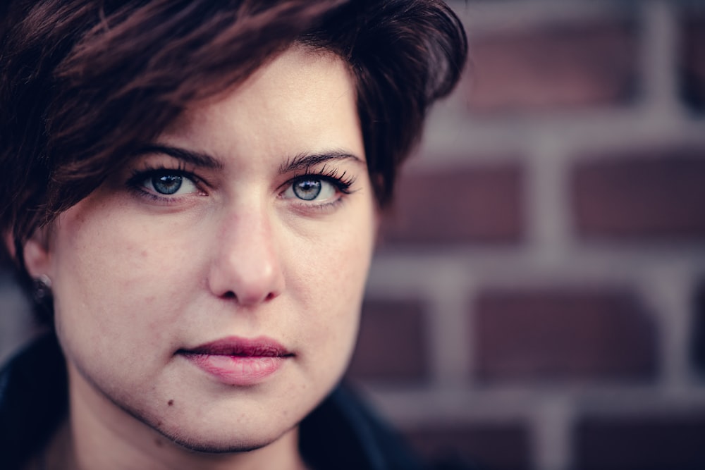 a close up of a person near a brick wall