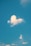 A cloud in the shape of a heart against a clear blue sky, with a few smaller clouds scattered around.