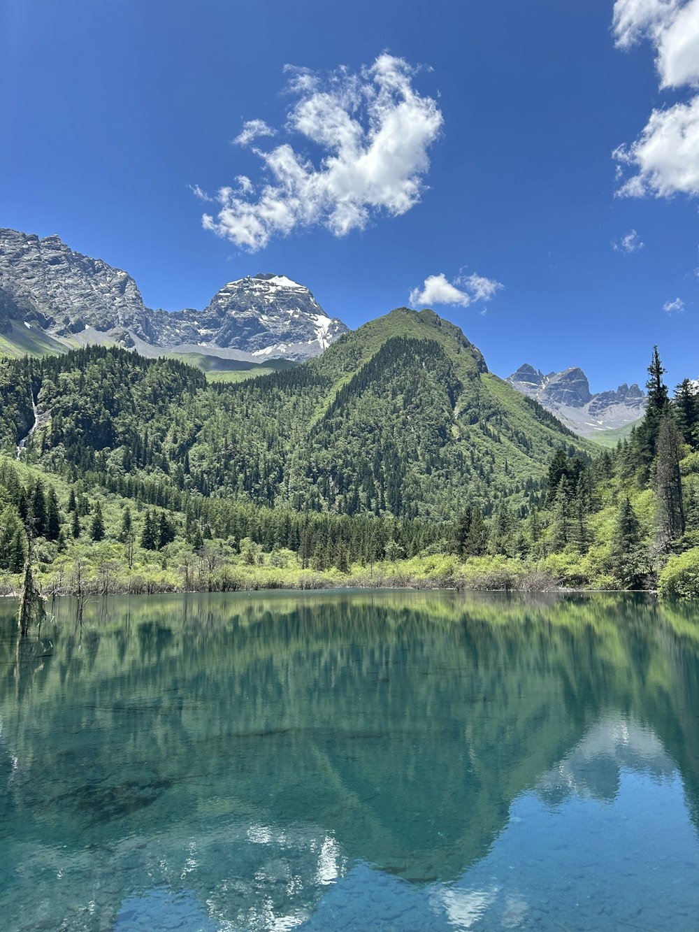 a lake surrounded by mountains under a blue sky