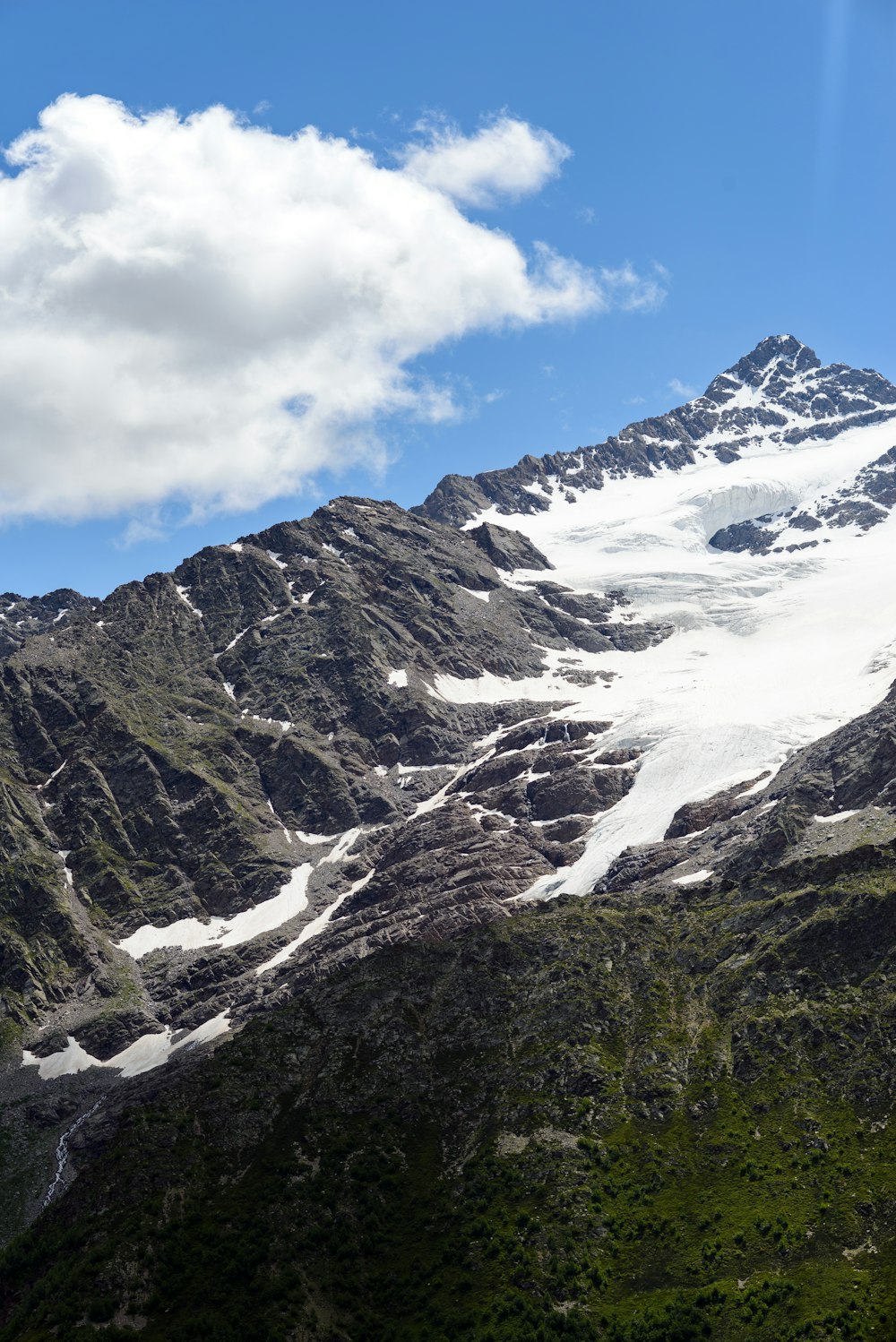 a snow covered mountain with a few clouds in the sky