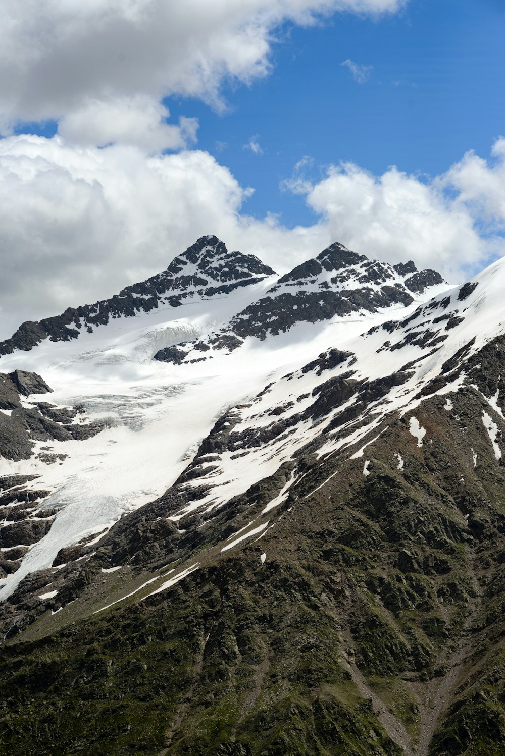 Una catena montuosa coperta di neve sotto un cielo blu nuvoloso