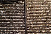 An array of decorative rings is organized in neat horizontal rows against a dark fabric background. Each ring features a variety of gemstones and intricate designs, showcasing a colorful and diverse assortment.