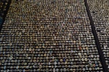 An extensive display of various rings arranged in neat rows. The rings showcase an array of gemstones in different colors and sizes, with intricate designs and settings. The background is a dark surface that highlights the sparkling jewels.