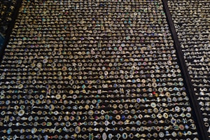 An extensive display of various rings arranged in neat rows. The rings showcase an array of gemstones in different colors and sizes, with intricate designs and settings. The background is a dark surface that highlights the sparkling jewels.