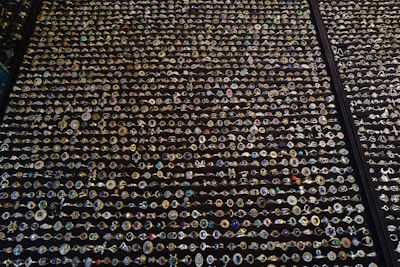An extensive display of various rings arranged in neat rows. The rings showcase an array of gemstones in different colors and sizes, with intricate designs and settings. The background is a dark surface that highlights the sparkling jewels.