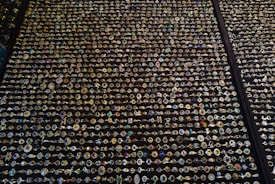 An extensive display of various rings arranged in neat rows. The rings showcase an array of gemstones in different colors and sizes, with intricate designs and settings. The background is a dark surface that highlights the sparkling jewels.