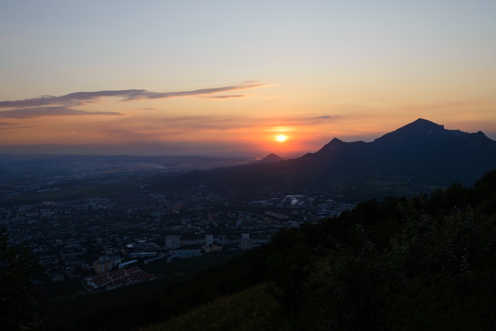 the sun is setting over a city and mountains