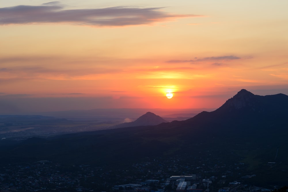 o sol está se pondo sobre uma cidade e montanhas