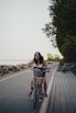 Smiling woman pausing with her bike beside coastal cliffs with ocean view in late afternoon light