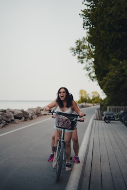 Smiling woman pausing with her bike beside coastal cliffs with ocean view in late afternoon light