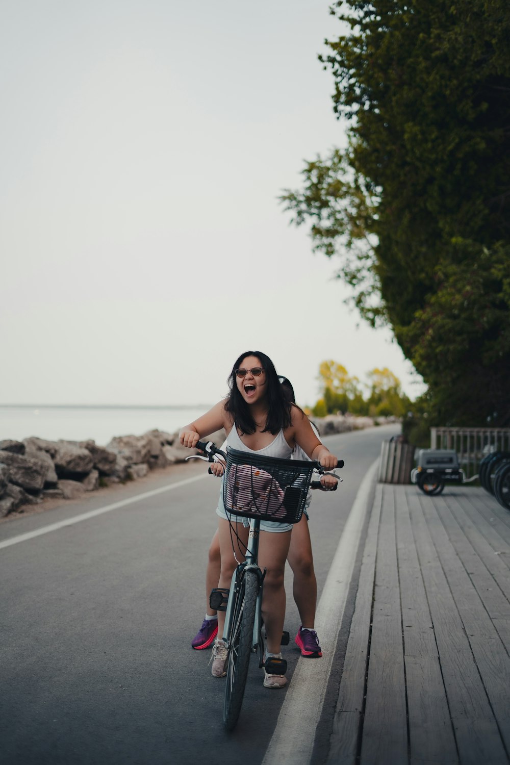 a woman riding a bike down a road next to the ocean