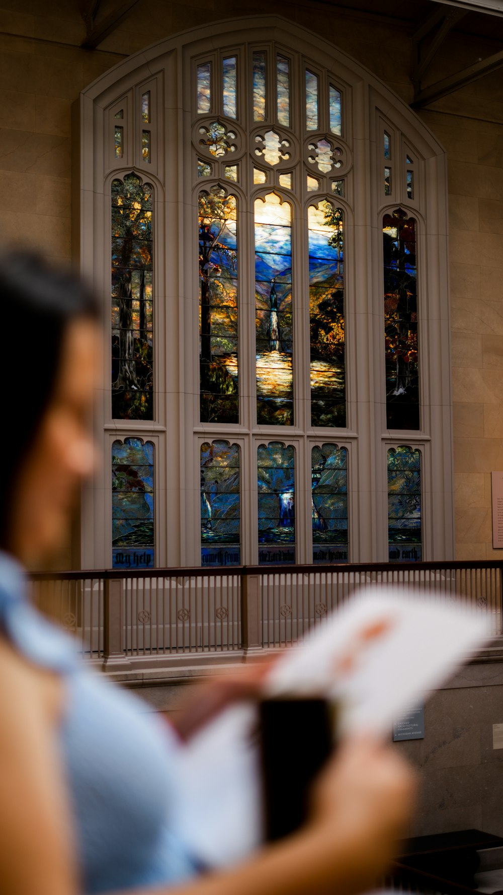 a woman reading a book in front of a stained glass window