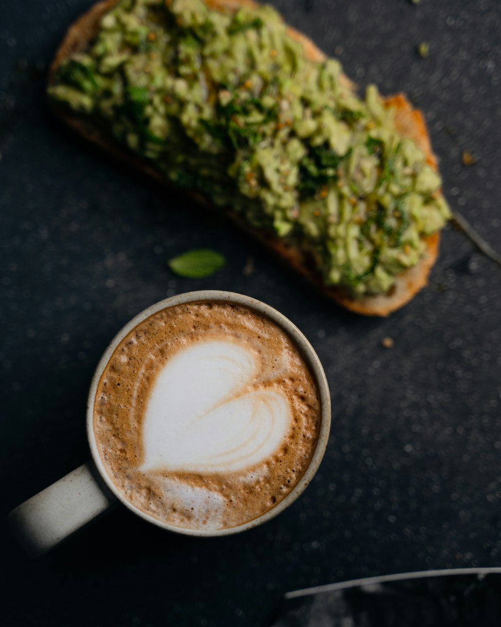 a cup of coffee sitting next to a piece of bread