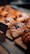 Several golden-brown pastries rest on a wooden board, each topped with powdered sugar and a dollop of dark jam. The pastries are arranged in a display setting, possibly in a bakery or cafe.
