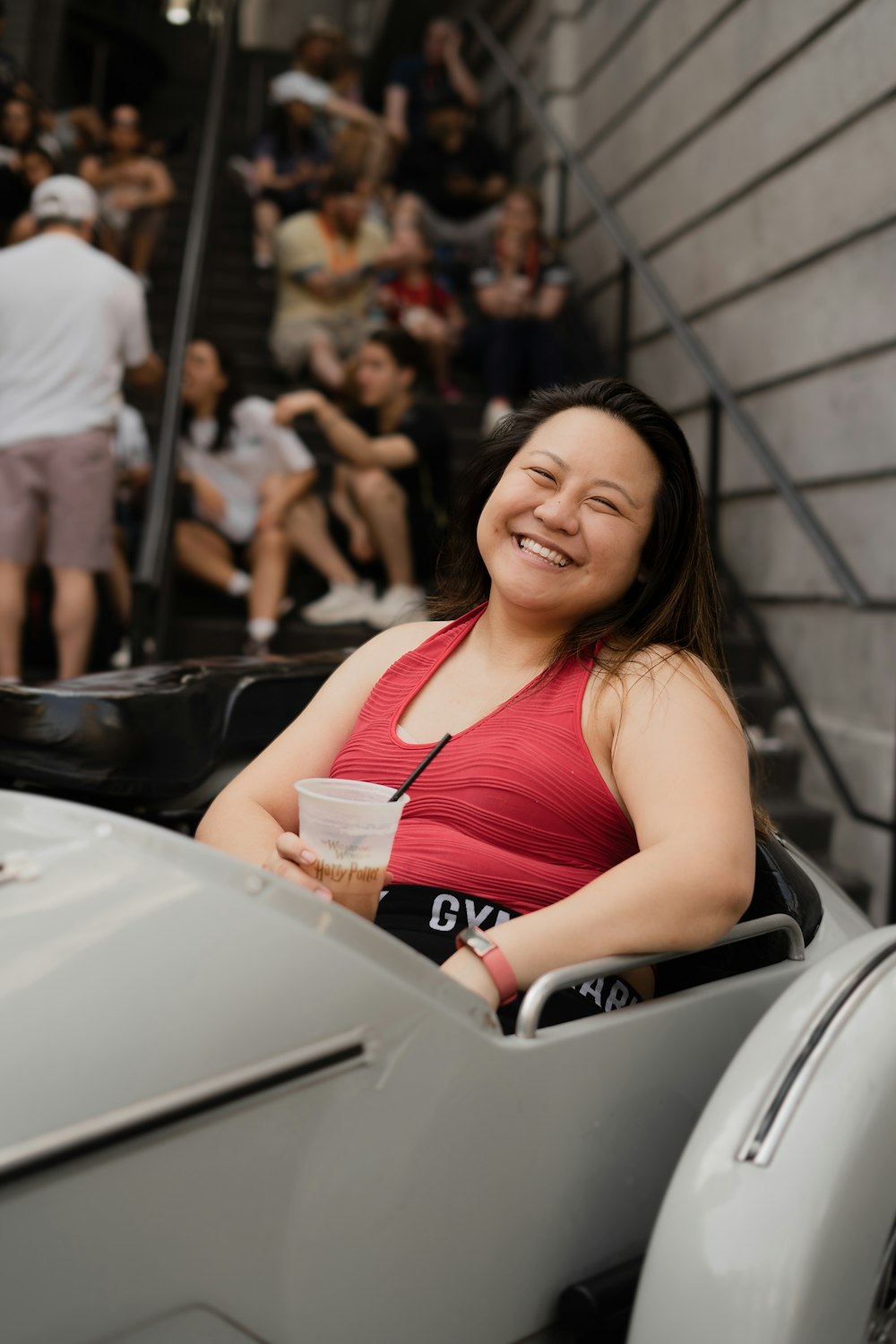a woman in a red tank top sitting in a car
