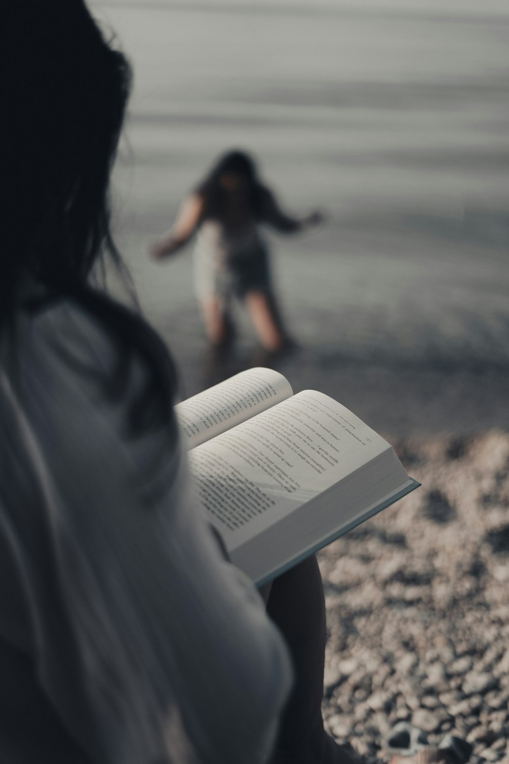 a woman is reading a book on the beach