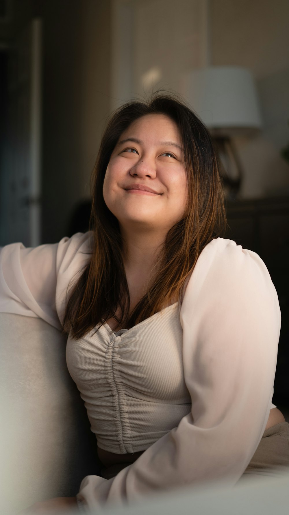 a woman sitting on a couch smiling at the camera