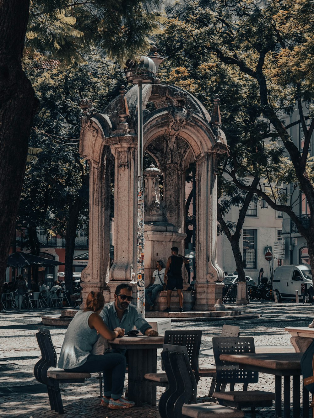 a man and woman sitting at a table in front of a fountain