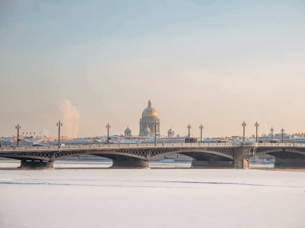 a bridge over a frozen river with a building in the background