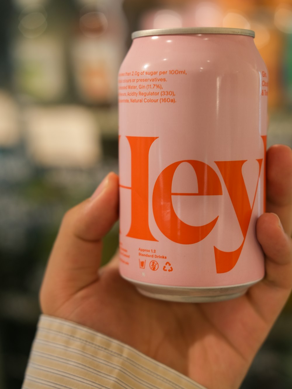 a hand holding a pink and orange can of jely