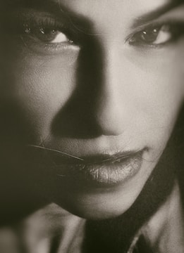 Monochrome close-up of a model with sharp shadows highlighting facial features.