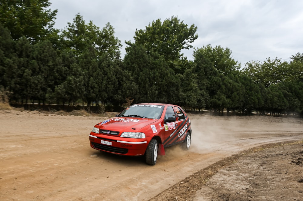 a red car driving down a dirt road