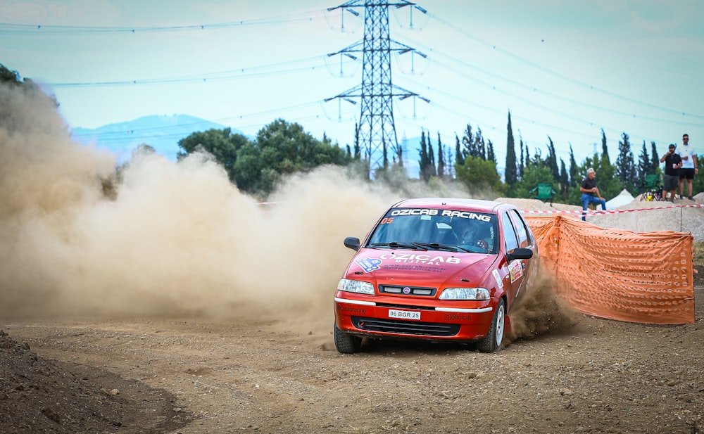 a red car driving down a dirt road