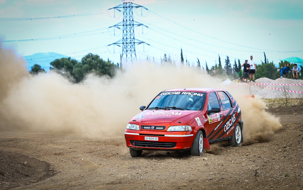 a red car driving down a dirt road