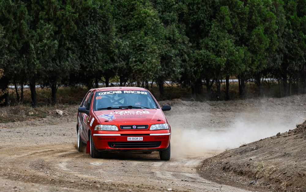 a red car driving down a dirt road