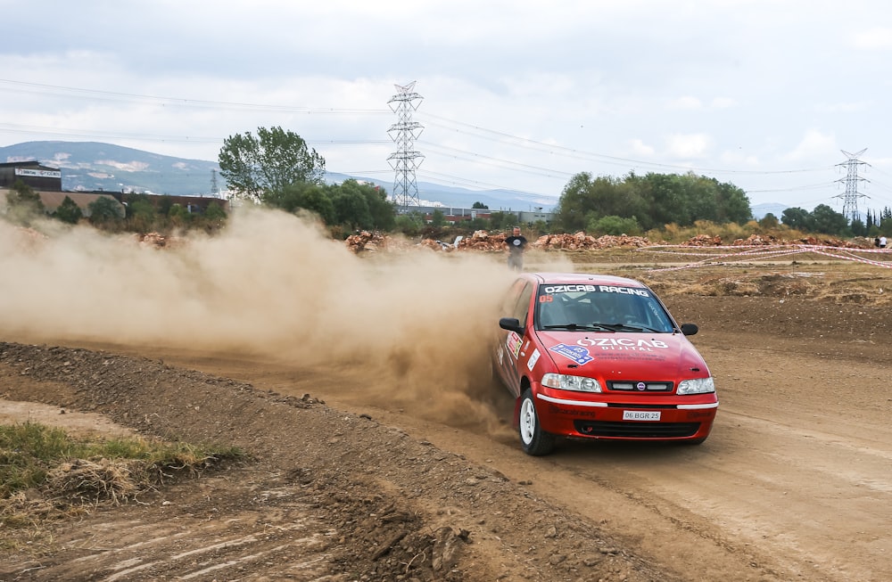 a red car driving down a dirt road