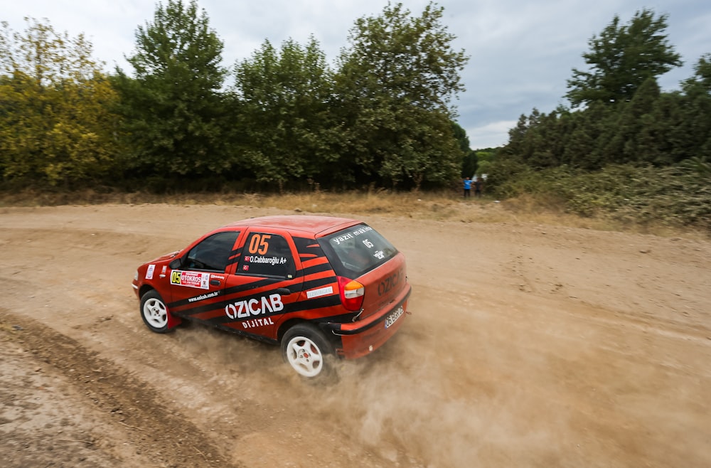 a red car driving down a dirt road