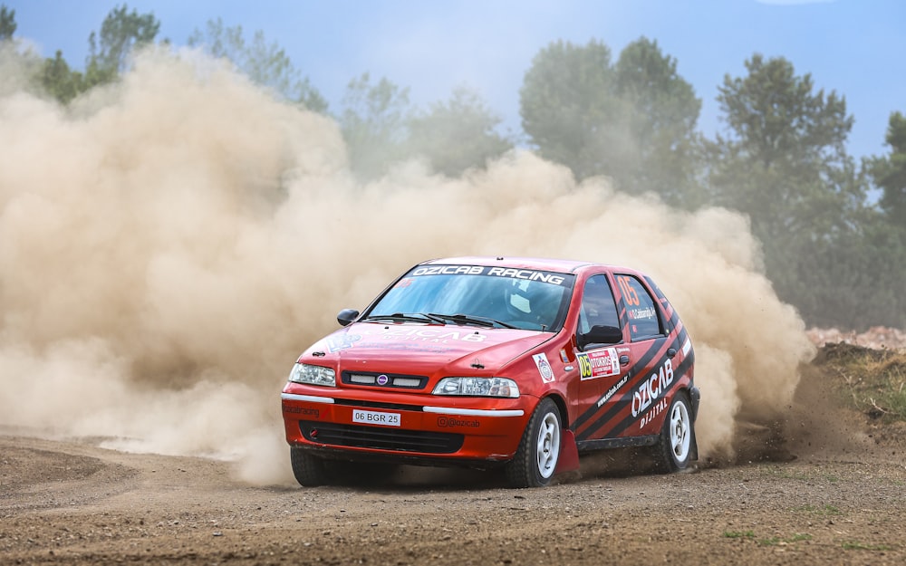 a red car driving down a dirt road