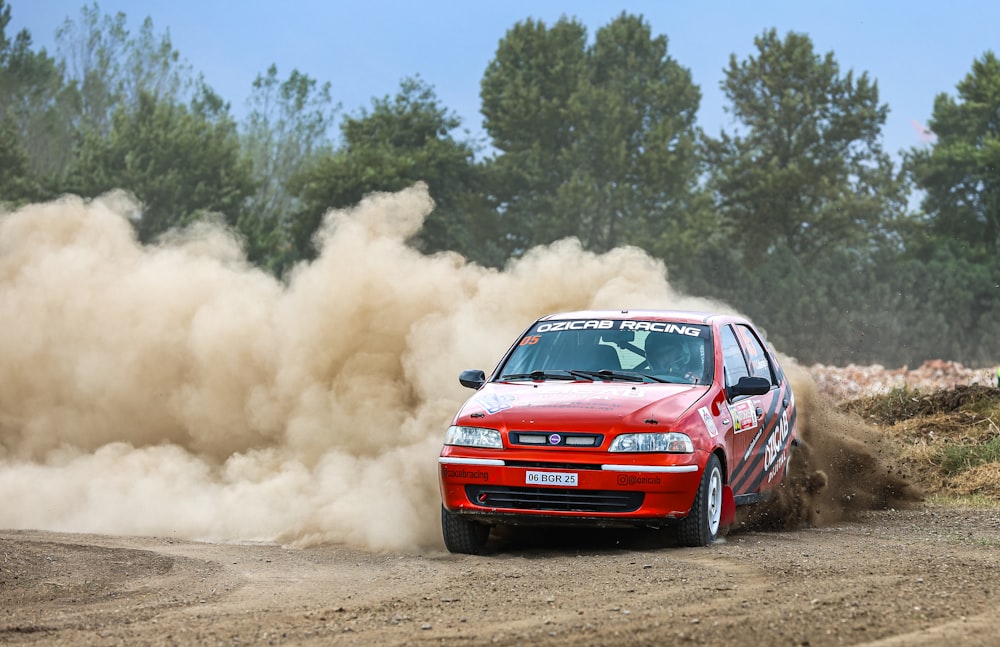 a red car driving down a dirt road