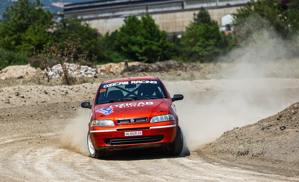 a red car driving down a dirt road