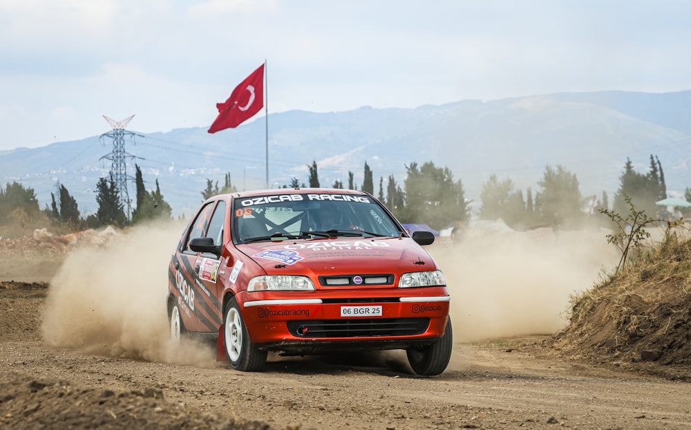 a red car driving down a dirt road